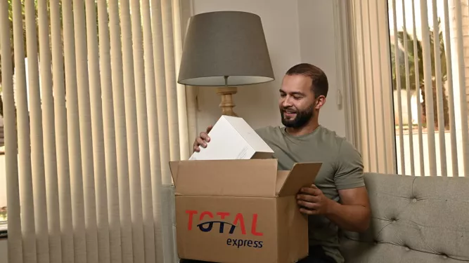Homem recebendo uma encomenda através de entrega standard, mostrando a embalagem da Total Express.