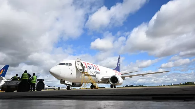 Avião de transporte aéreo de carga no aeroporto, com operários realizando atividades de carga e descarga.