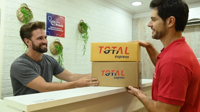 Homem entrega encomendas em um balcão de atendimento, utilizando a conveniência do serviço de drop off para logística.