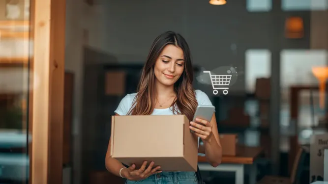 Mulher sorridente segura uma caixa de encomenda e um smartphone com ícone de carrinho, representando uma excelente experiência de compra.