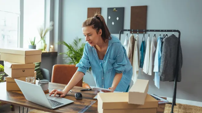 Mulher organiza encomendas no notebook, uma das ideias de negócios com pouco dinheiro.