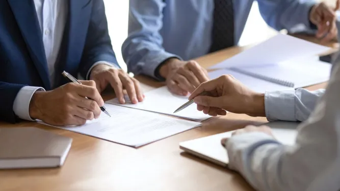 Empresários assinando documentos legais sobre o que é razão social.