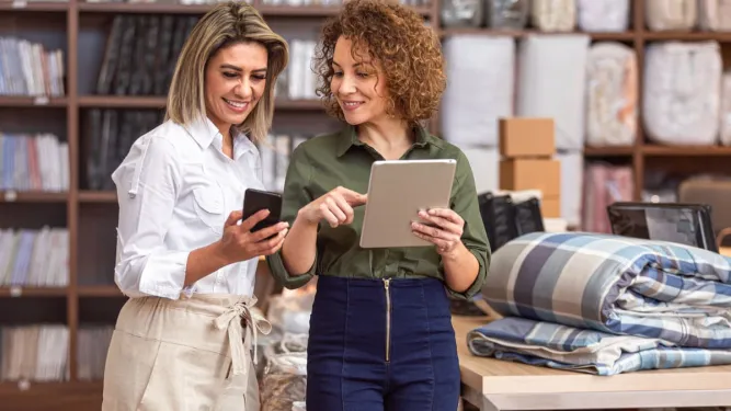 Duas profissionais a gerir encomendas no tablet dentro de uma dark store.