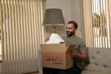 Homem recebendo uma encomenda através de entrega standard, mostrando a embalagem da Total Express.