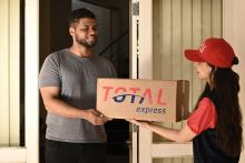 Funcionária da Total Express fazendo uma entrega à domicílio de frete courier a um cliente
