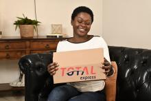 Mulher abraça caixa com encomenda da Total Express. Ela está contente com o pós-venda da loja
