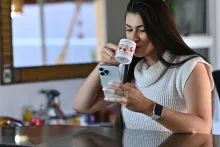 Mulher bebe café enquanto olha no celular o rastreamento de encomendas 