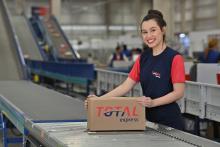 Funcionária recolhe encomenda sobre esteira que facilita a eficiência logística