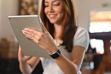 Jovem sorrindo enquanto navega em um tablet e usa um smartwatch, mostrando a facilidade e os benefícios de fazer compras online através do instagram shopping.