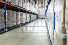 Galpão logístico organizado com caixas empilhadas, mostrando os cuidados na armazenagem.