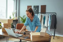 Mulher organiza encomendas no notebook, uma das ideias de negócios com pouco dinheiro.
