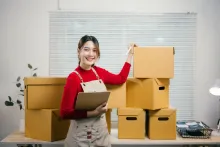 Mulher com prancheta confere caixas de mercadorias para importar e exportar.