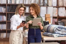 Duas profissionais a gerir encomendas no tablet dentro de uma dark store.