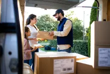 Entregador conferindo pacote com cliente na última milha da gestão de riscos em logística.