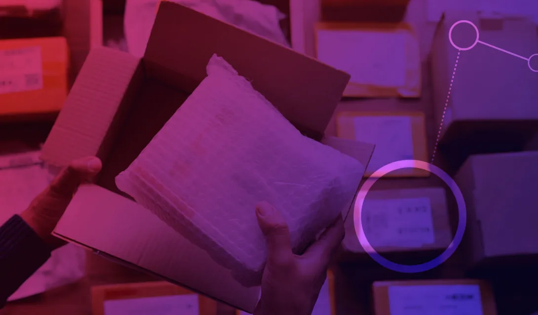 Uma mão segurando um plástico bolha e ao fundo diversas caixas de encomenda