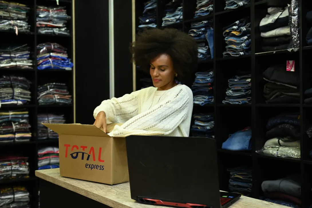 mulher negra em loja de roupa embalando produtos para enviar com a Total Express na black friday