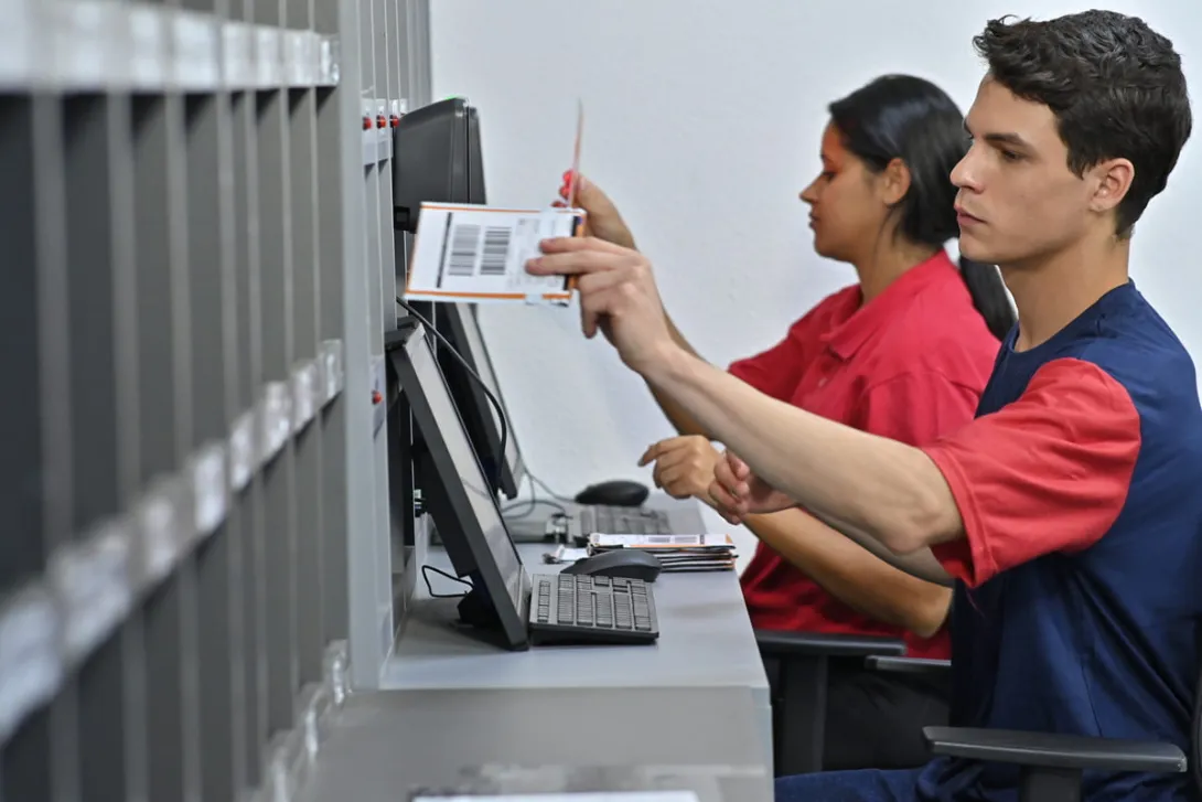 Duas pessoas atendendo o público e realizando entrega de cartões.