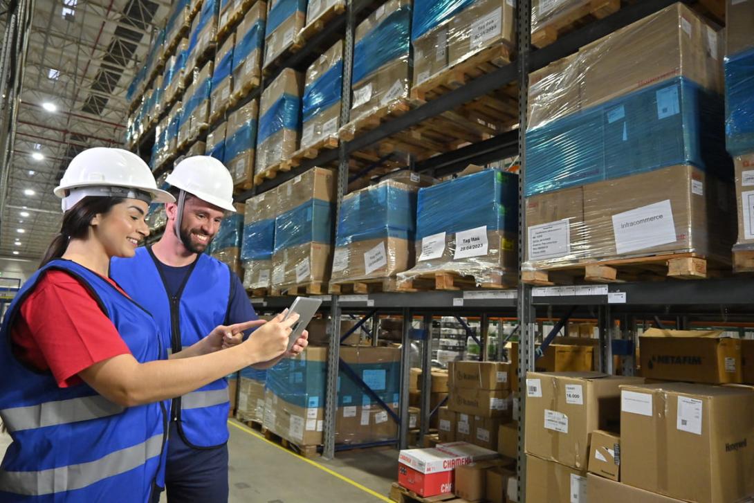 Duas pessoas com equipamentos de segurança realizando a gestão logística.