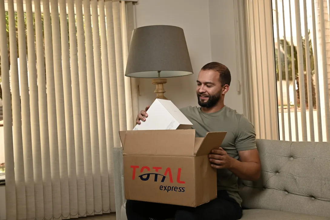 Homem recebendo uma encomenda através de entrega standard, mostrando a embalagem da Total Express.