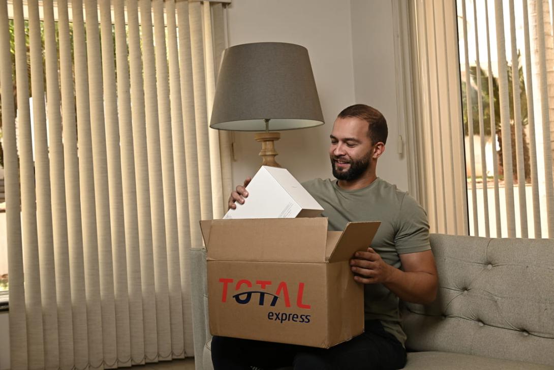 Homem recebendo uma encomenda através de entrega standard, mostrando a embalagem da Total Express.