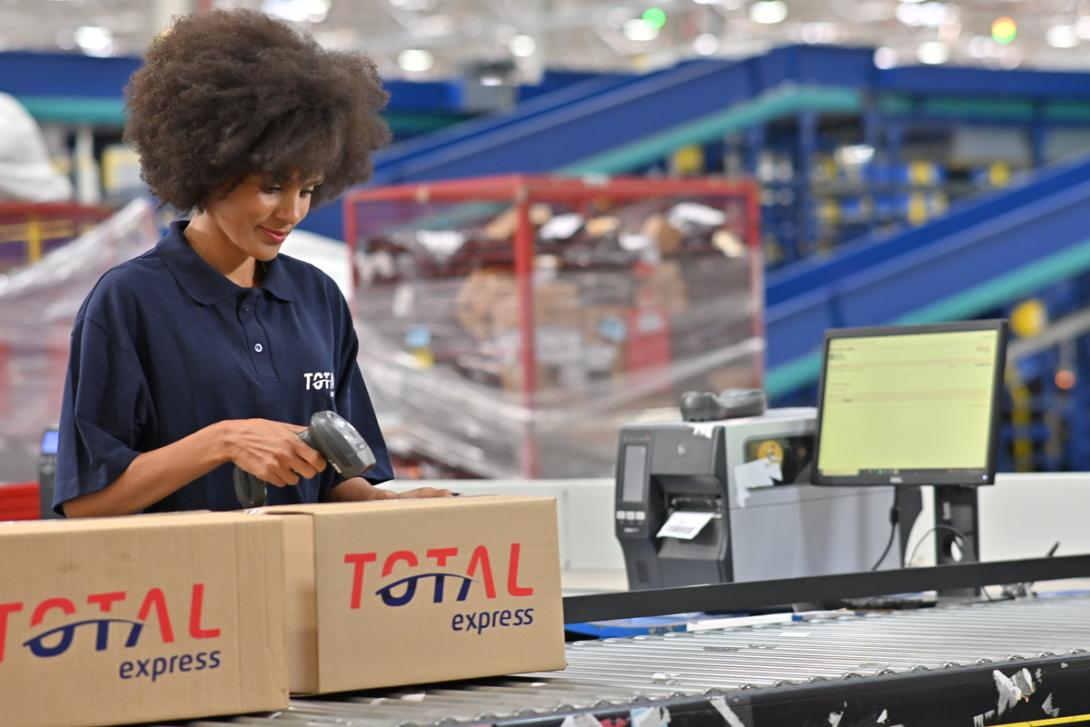 Mulher trabalha no setor logístico empacotando encomendas para distribuição em ponto de coleta