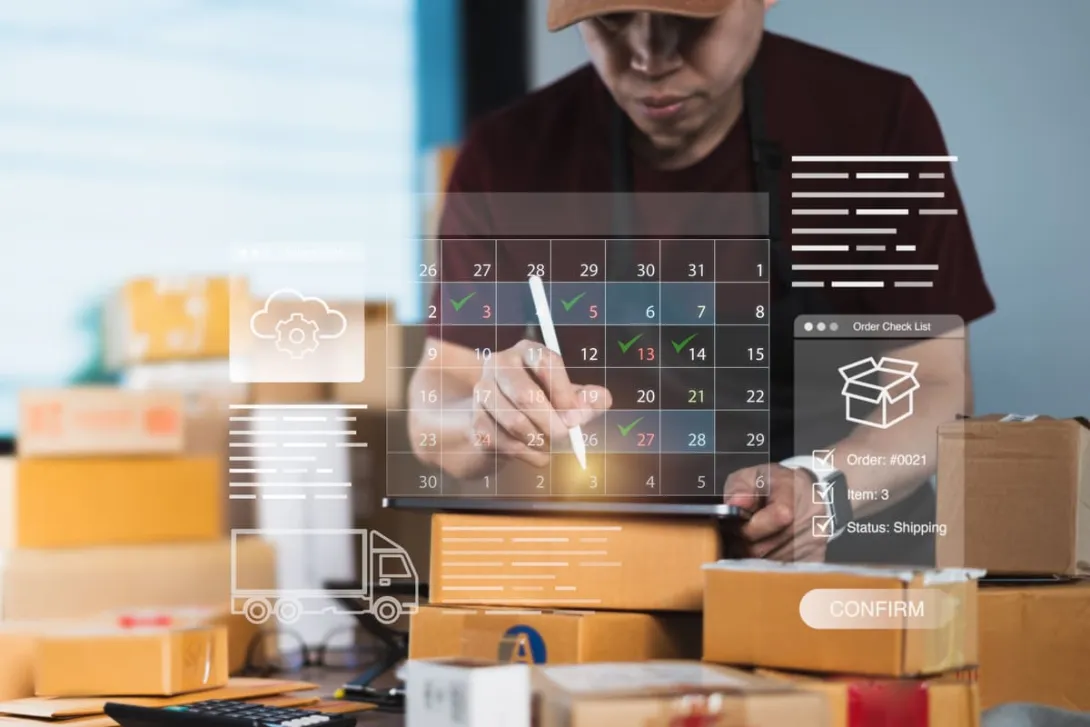 Pessoa com tablet organiza datas em um calendário digital flutuante cercada por pacotes, exemplificando o uso de um calendário para e-commerce.