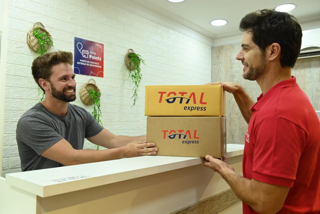 Homem entrega encomendas em um balcão de atendimento, utilizando a conveniência do serviço de drop off para logística.
