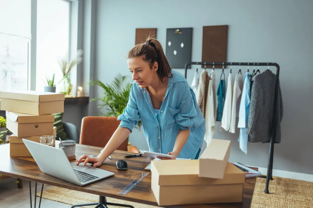Mulher organiza encomendas no notebook, uma das ideias de negócios com pouco dinheiro.