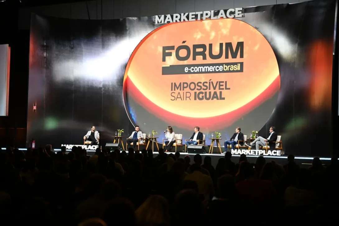 Palestrantes debatem no palco do Fórum E-Commerce Brasil diante de uma plateia.